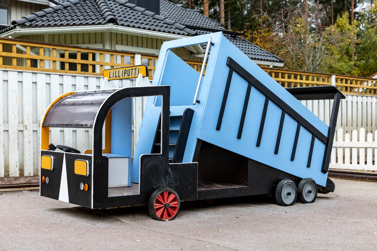 Leikkikuorma-auto ja Lilliputti-kyltti Päiväkoti Lilliputin pihalla.